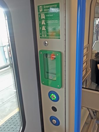 Door open and close buttons, plus emergency door release, in a vestibule.